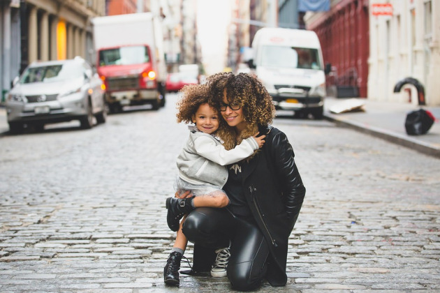 Smiling mixed race mother with child crouched down in street 